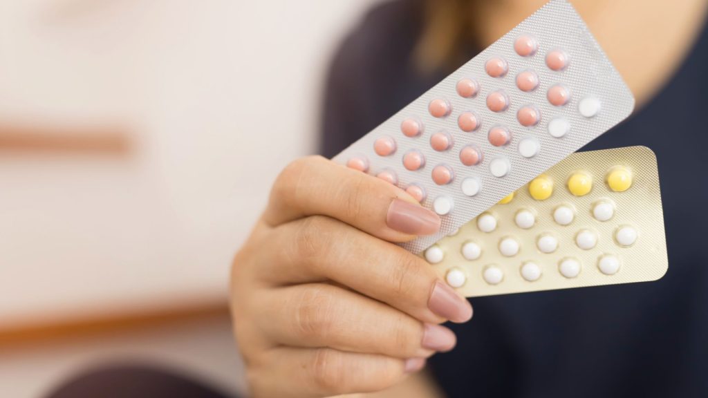 Pokazywane przez kobietę na zdjęciu tabletki antykoncepcyjne powodują trądzik, ale nie zawsze.